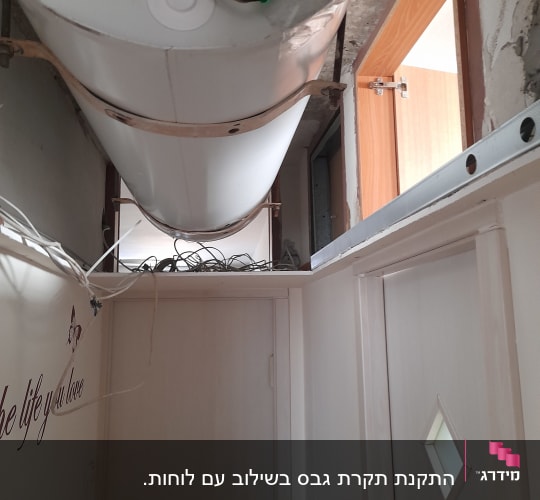 דוד מים מותקן על תקרה עם צינורות חשופים